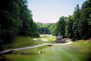 Un campo da golf con uno stagno, un sentiero pedonale e un padiglione.