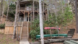 A cabin with a wooden deck, a staircase, and a covered seating area. - Lakeside at Rumbling Bald (Lake Lure)