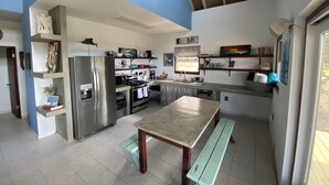 A compact kitchen with modern appliances, a wooden table, and a bench.