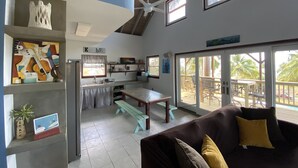 A spacious living area with a kitchen, a dining table, and a balcony with outdoor seating.