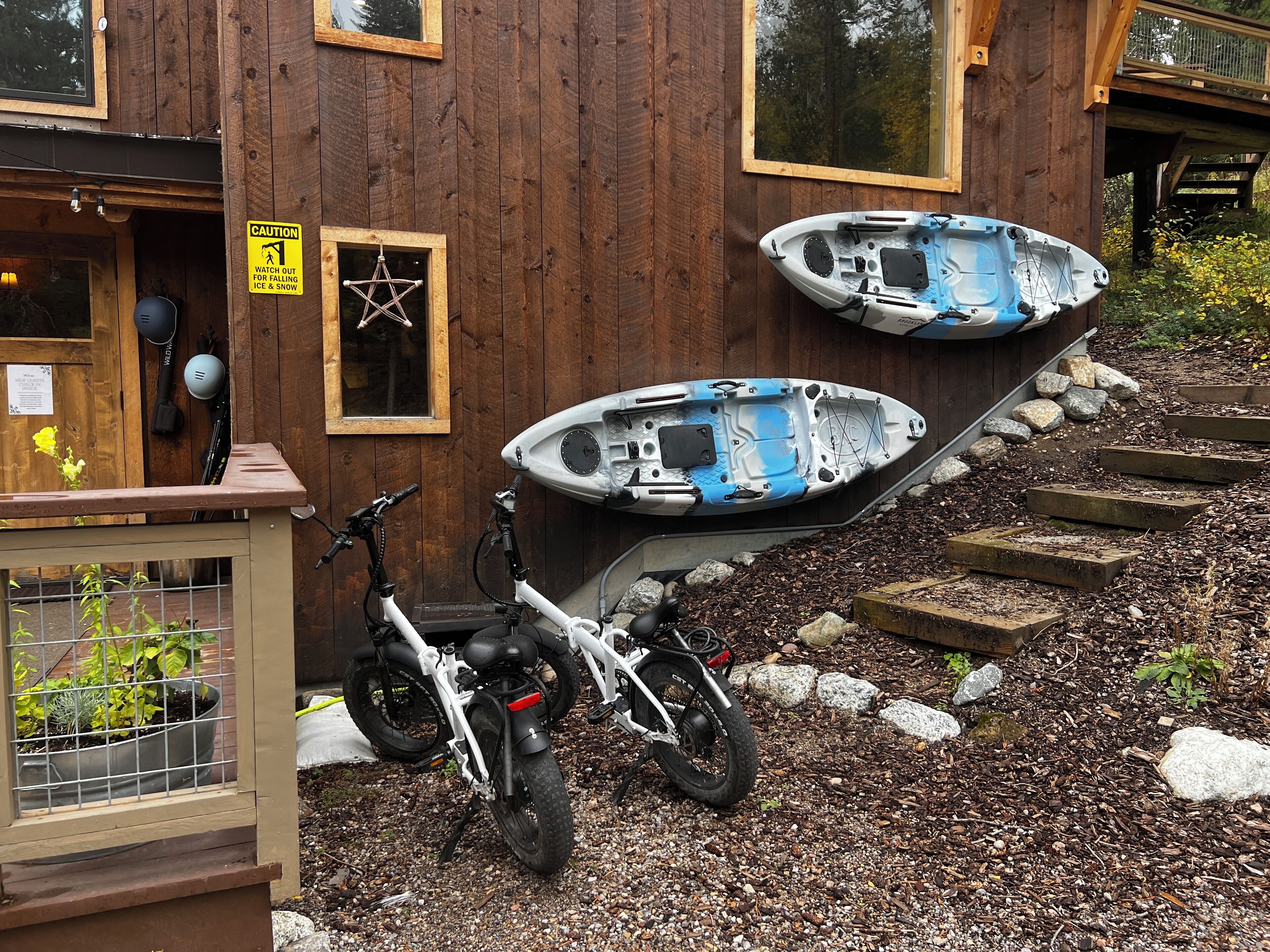 Un edificio in legno con kayak e una bicicletta parcheggiate fuori.