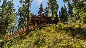 A wooden cabin with multiple balconies, surrounded by dense forest and a wooden staircase leading up to it. - Jackson Hole Hideout Entire Home, Perfect for a Micro Wedding, Corporate Retreat (Wilson)
