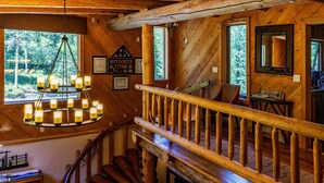 A wooden interior with a staircase, a chandelier, and framed items on the walls. - Jackson Hole Hideout Entire Home, Perfect for a Micro Wedding, Corporate Retreat (Wilson)