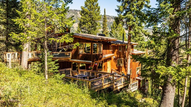 A multi-level wooden cabin surrounded by dense forest. - Jackson Hole Hideout Entire Home, Perfect for a Micro Wedding, Corporate Retreat (Wilson)