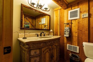 A rustic bathroom with a wooden vanity, a large mirror, and a ceiling-mounted deer antler light fixture. - Jackson Hole Hideout Entire Home, Perfect for a Micro Wedding, Corporate Retreat (Wilson)