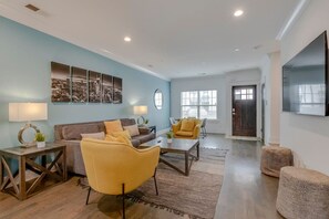 A living room with a sofa, armchairs, a coffee table, and a TV.