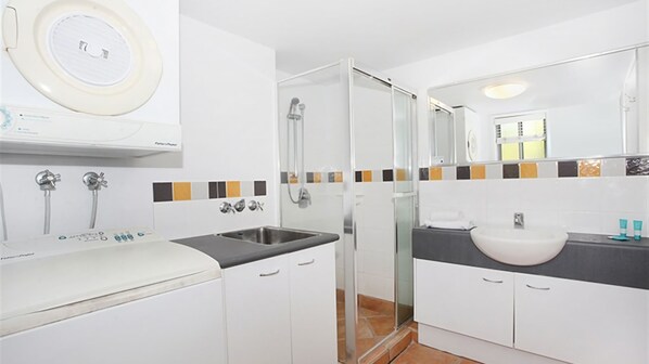A modern bathroom with a sink, mirror, shower, and a toilet. - Unit 13 'Seacove Resort' (Coolum Beach)