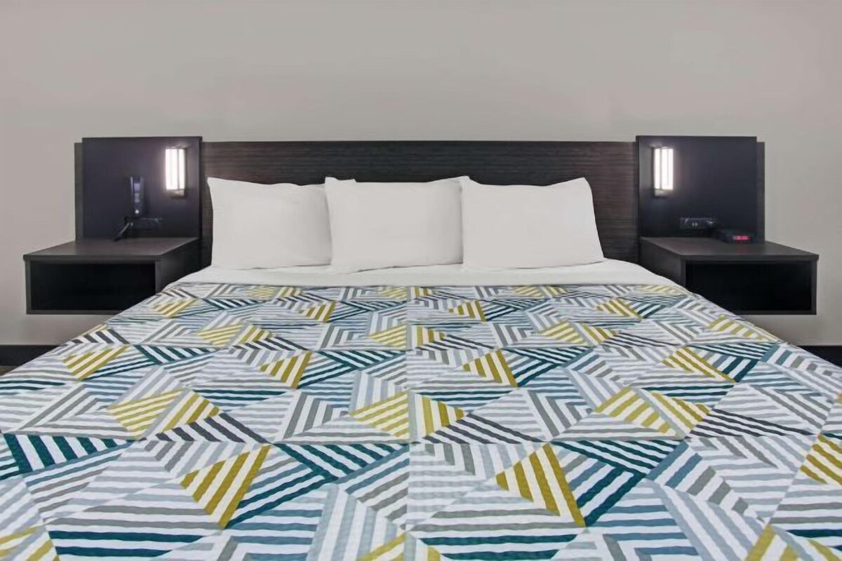 A hotel room with a bed, two bedside tables, and a nightstand.