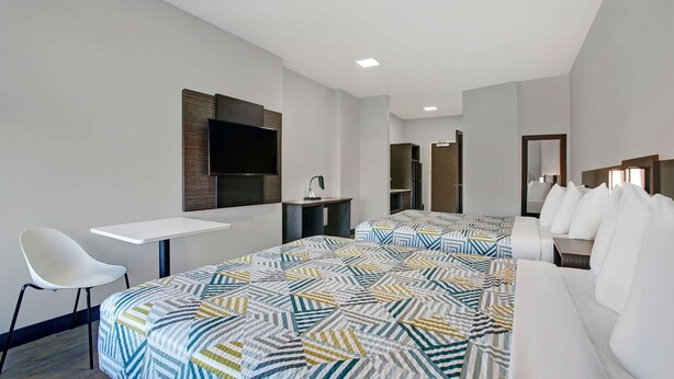 A hotel room with two beds, a desk, a chair, a TV, and a wardrobe. - Motel 6 Monahans, TX (Monahans)