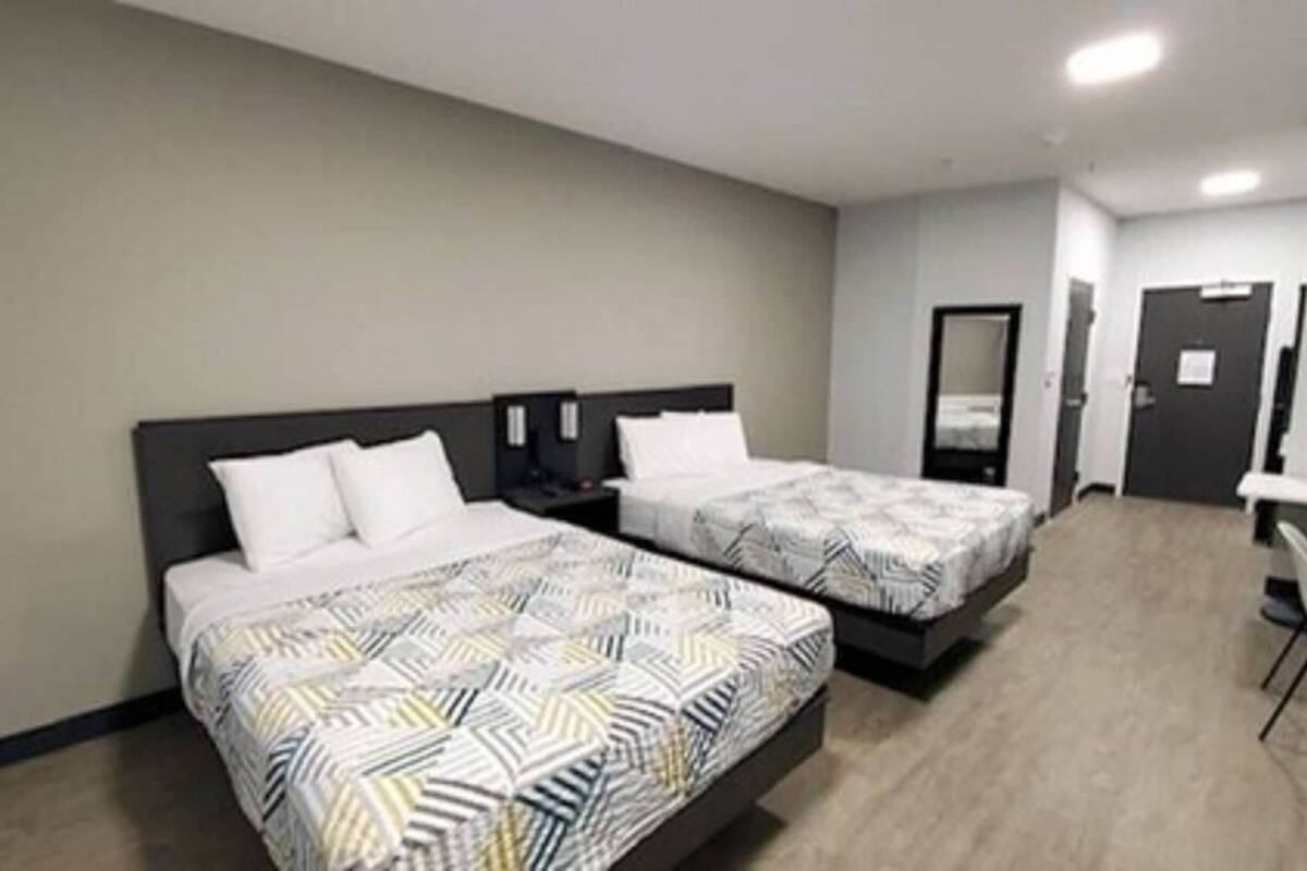 Une chambre d’hôtel avec deux lits, chacun recouvert d’une couvre-lit à motifs, une table de chevet et une lampe fixée au mur.