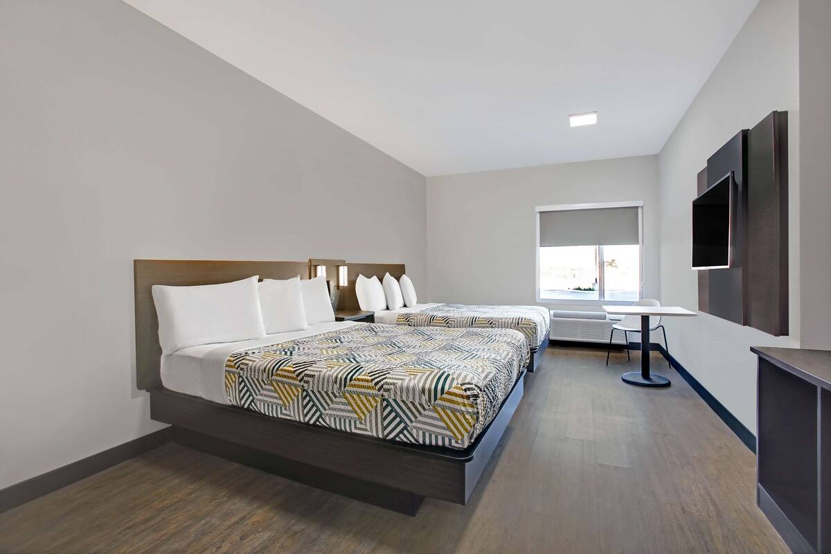 Une chambre d’hôtel avec deux lits, un bureau et une télévision.