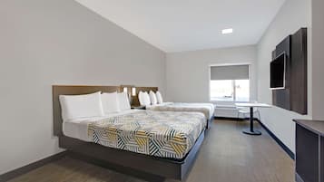 A hotel room with two beds, a desk, and a TV.