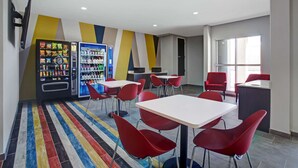 A modern dining area with red chairs, white tables, and vending machines. - Motel 6 Monahans, TX (Monahans)