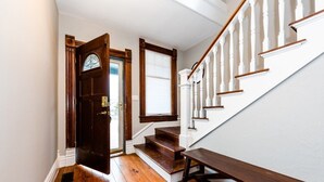 A wooden staircase with white balusters and a dark wooden door with a glass window.