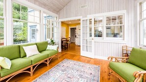 A spacious room with a green sofa, wicker chairs, and a patterned rug.