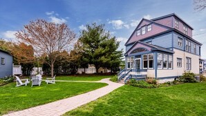 A two-story house with a front porch and a pathway leading to the entrance.