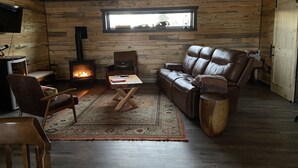 Uma sala de estar aconchegante com lareira, sofá de couro, piso de madeira e uma janela grande.