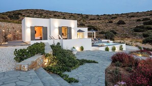 Una villa moderna con facciata in pietra, piscina e giardino curato.