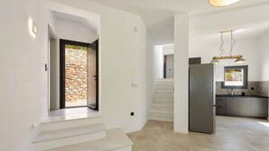 Una cucina moderna con frigorifero integrato, una zona pranzo con tavolo e sedie, e una scala che conduce a un piano superiore.