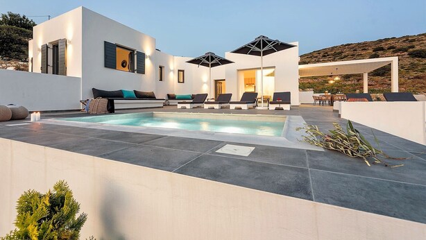 Un'area piscina moderna con piscina, sedie a sdraio e una zona salotto coperta.