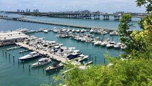 A marina with numerous boats docked, a bridge in the background, and a city skyline across the water. - Sunshine Miami Vacation ☀️ (Miami)