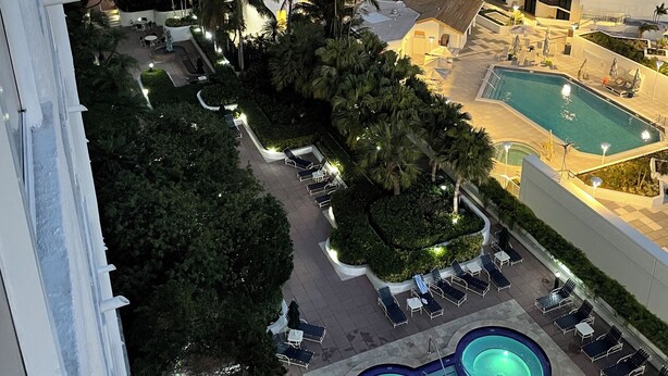A high-rise hotel with multiple balconies, a pool area with lounge chairs, and a view of the sea. - Sunshine Miami Vacation ☀️ (Miami)