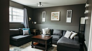 A living room with a dark gray sofa set, a wooden coffee table, and a patterned rug.