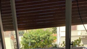 A balcony with a yellow sofa, two decorative pillows, and a view of a tree and buildings. - 2 bedroom private vacation home in carrara (Carrara)