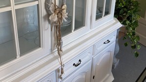 A white, ornate cabinet with multiple glass doors and drawers, featuring a decorative wreath and seashells. - 2 bedroom private vacation home in carrara (Carrara)
