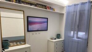 A bedroom with a bed, a dresser, a mirror, a television, and a window with a curtain. - 2 bedroom private vacation home in carrara (Carrara)