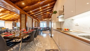 Un comedor moderno con techo de madera, pared de ladrillo y cocina con encimera de mármol y pileta.