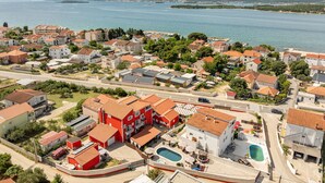An aerial view of a coastal residential area with houses, a swimming pool, and a marina.
