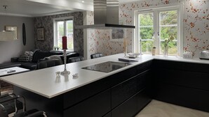 A modern kitchen with a central island, black cabinetry, and a window with a view of greenery. - Oas 300m ifrån centrum Uddevalla -  Bubbelpool uteplats (Västra Götalands län)