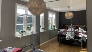 A modern bedroom with a large mirror, a round chandelier, and a bed with floral bedding. - Oas 300m ifrån centrum Uddevalla -  Bubbelpool uteplats (Västra Götalands län)