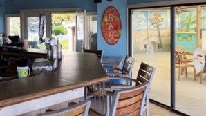 A restaurant with a bar area, wooden chairs, and ceiling fans. - Top Flr 3rd, Ocean View, Beach Bar & Rest, Nxt to Elevator, Pickleball & Tennis (Hilton Head Island)