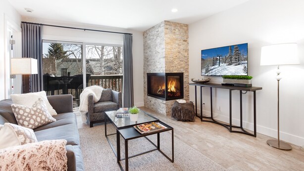 A modern living room with a fireplace, a sofa, a coffee table, and a TV mounted on the wall. - Ski, Hike, Bike out the door. Hot Tub, Hot Pools, Gym, Pickleball,Tennis Courts (Park City)