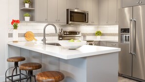 A modern kitchen with a large island, stainless steel appliances, and bar stools. - Ski, Hike, Bike out the door. Hot Tub, Hot Pools, Gym, Pickleball,Tennis Courts (Park City)
