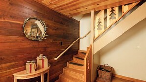 Un escalier en bois avec une rampe, un miroir au mur et une petite table sur laquelle sont posés des cadeaux emballés.