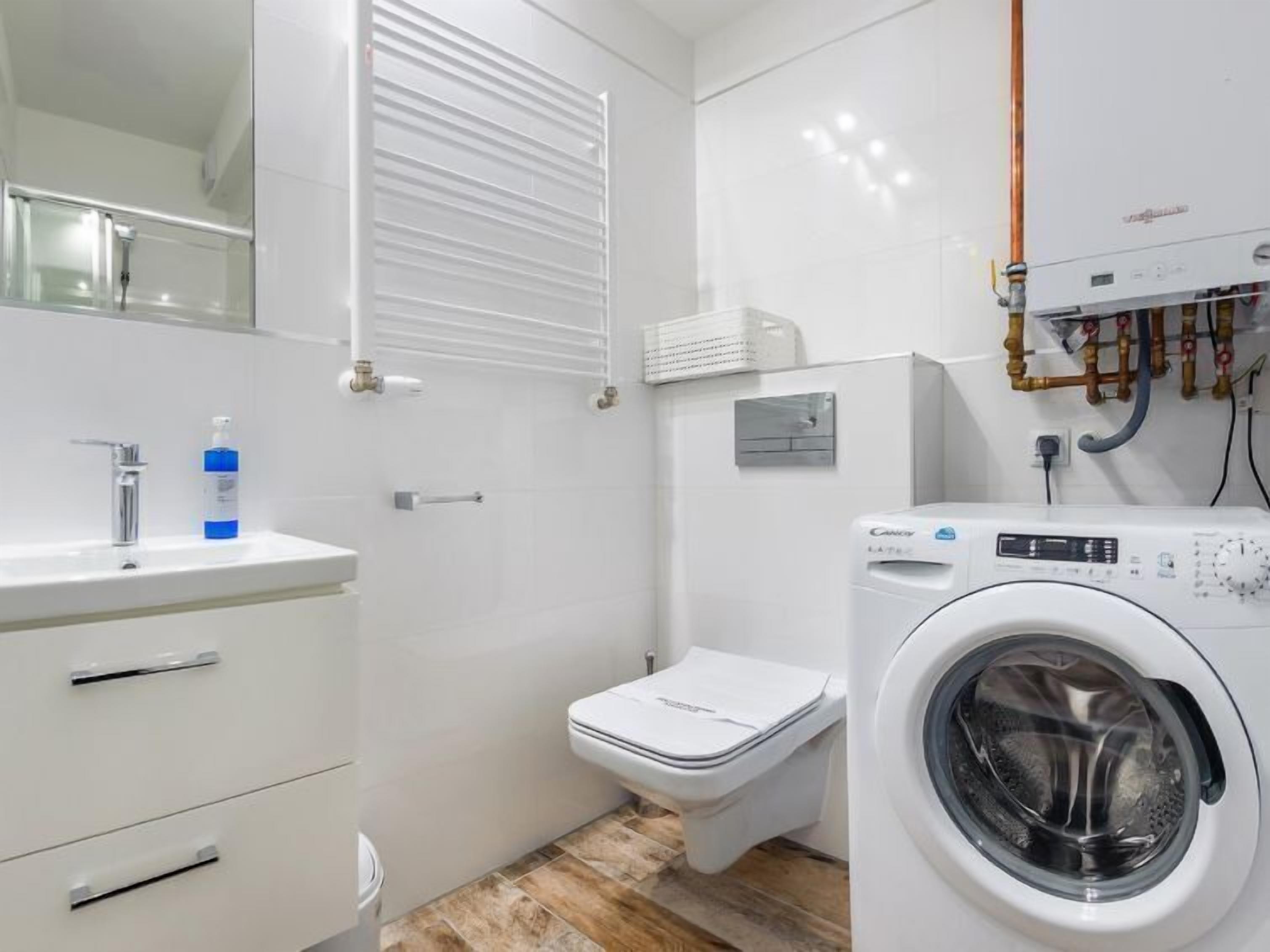 Un baño pequeño con lavamanos, inodoro y lavadora.
