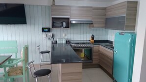 A compact kitchen with a microwave, stove, and teal refrigerator. - HERMOSO DEPA CENTRO HISTORICO (Guadalajara)