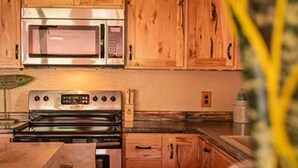 A kitchen with wooden cabinets, a microwave, an oven, and a refrigerator.