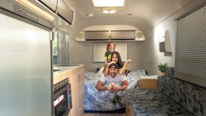 En kompakt autocamper indretning med et tekøkken, en seng og et siddeområde.