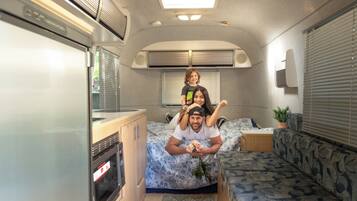 Interior compacto de autocaravana con kitchenette, cama y zona de estar.