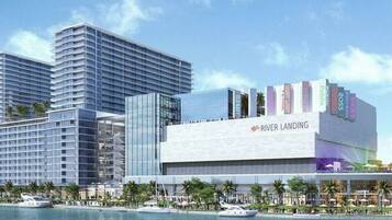 Un hotel moderno con un llamativo letrero que dice 'River Landing', edificios altos adyacentes y vista al río.