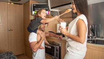 Cocina compacta con microondas, cafetera y televisor mostrando Netflix.