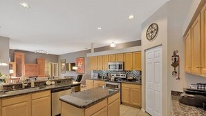 A spacious kitchen with granite countertops, wooden cabinets, a large island, and stainless steel appliances. - Spacious private pool home, close to beaches, with many upgrades! (Fort Myers)