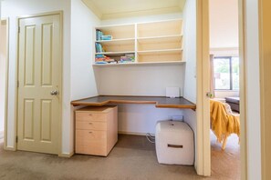 A study room with a desk, bookshelves, a chair, and a door. - Iles Inn - Spa Pool, Pets OK, Walk to Forest (Rotorua)