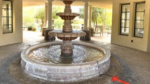 Une fontaine en pierre à plusieurs niveaux, située dans une cour bordée de colonnes et comprenant un bassin.