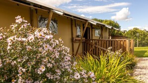 A yellow building with a wooden deck and a grassy yard. - Luxury Safari Lodge-Sleeps 4/6-Deer Park-Dogs Ok (Crediton)