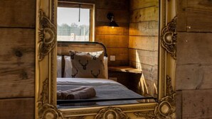 A wooden cabin room with a bed, a nightstand, and a window. - Luxury Safari Lodge-Sleeps 4/6-Deer Park-Dogs Ok (Crediton)